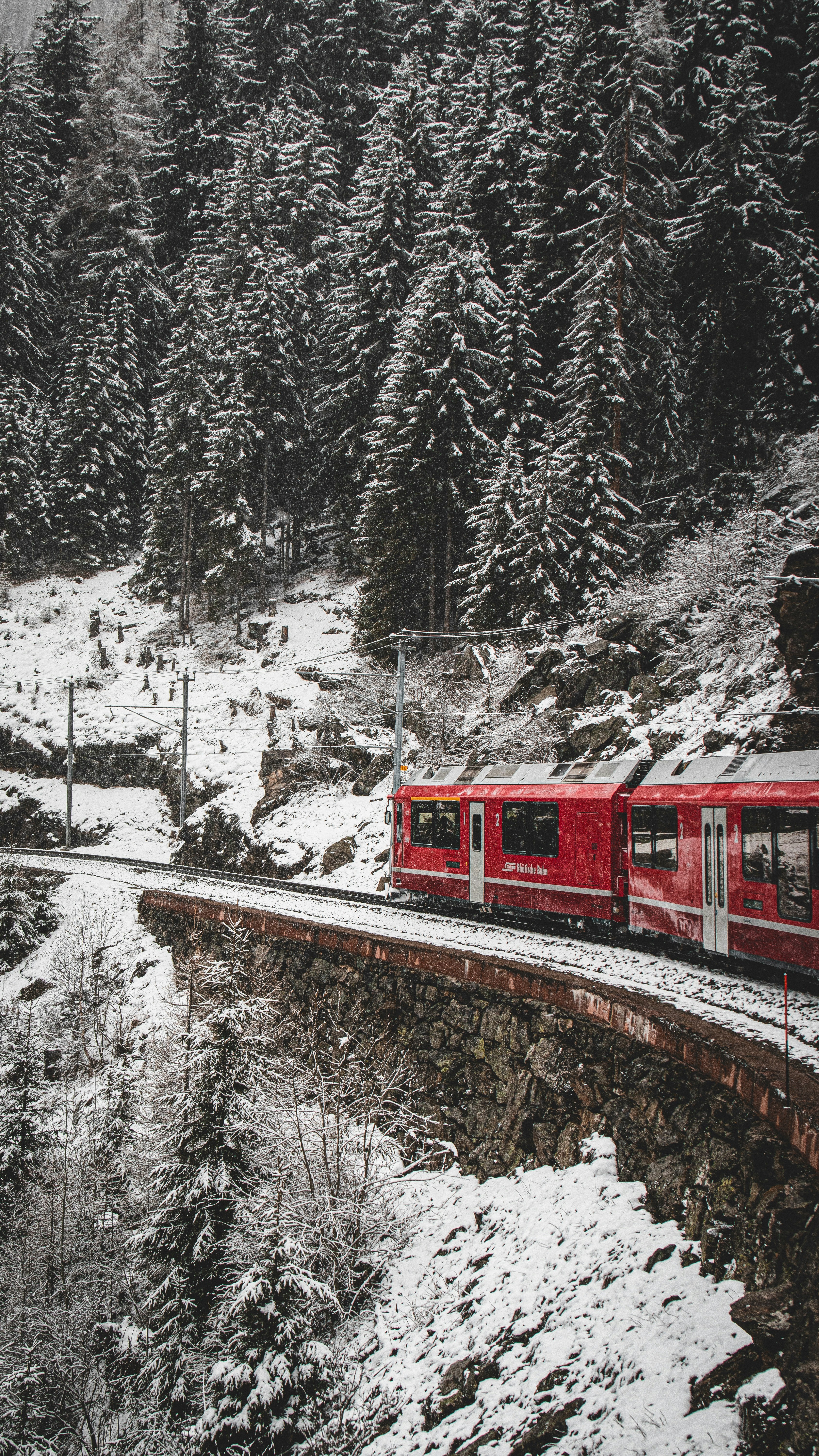 a red train traveling through a snow covered forest