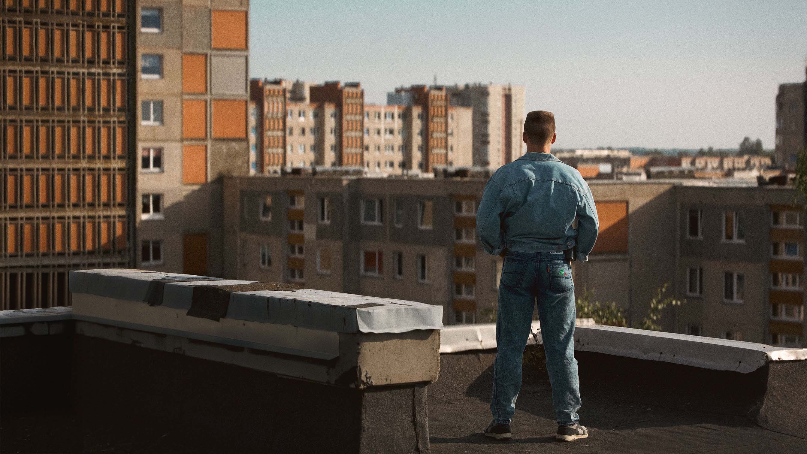 Džiugas Grinys as Rimants standing on a rooftop overlooking his district in The Southern Chronicles (Pietinia Kronikas) — an Oscar-nominated Lithuanian 90s coming-of-age comedy