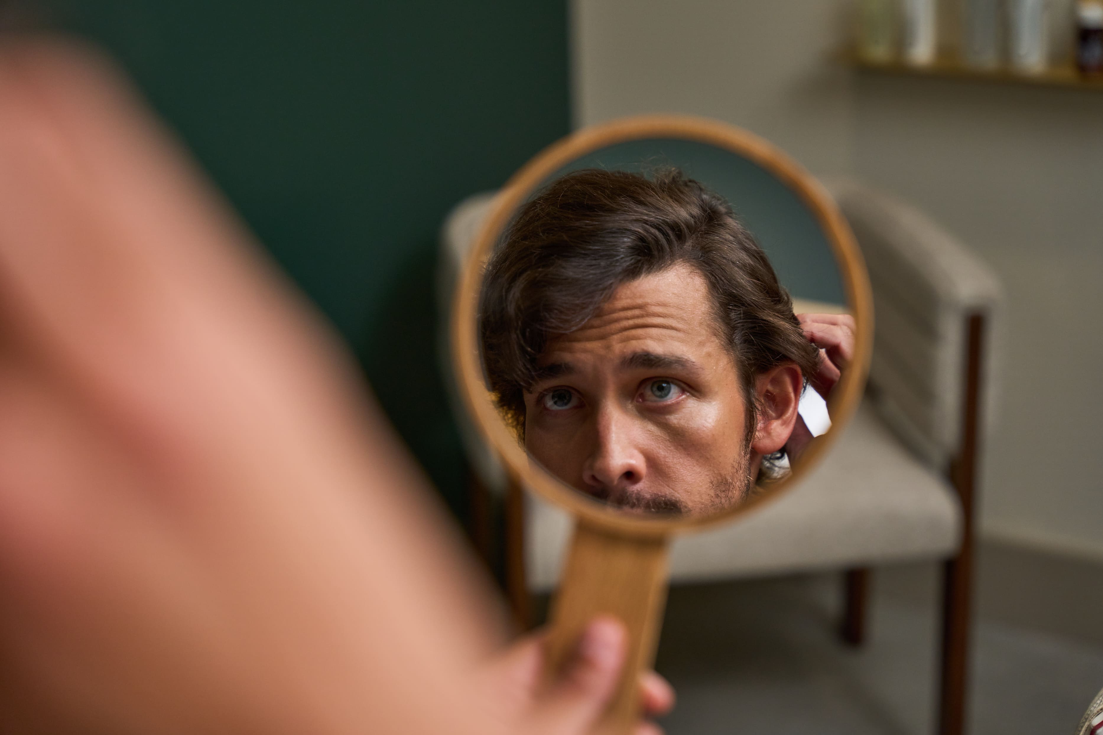 A hair care professional applying a treatment to a client's scalp in a salon setting.