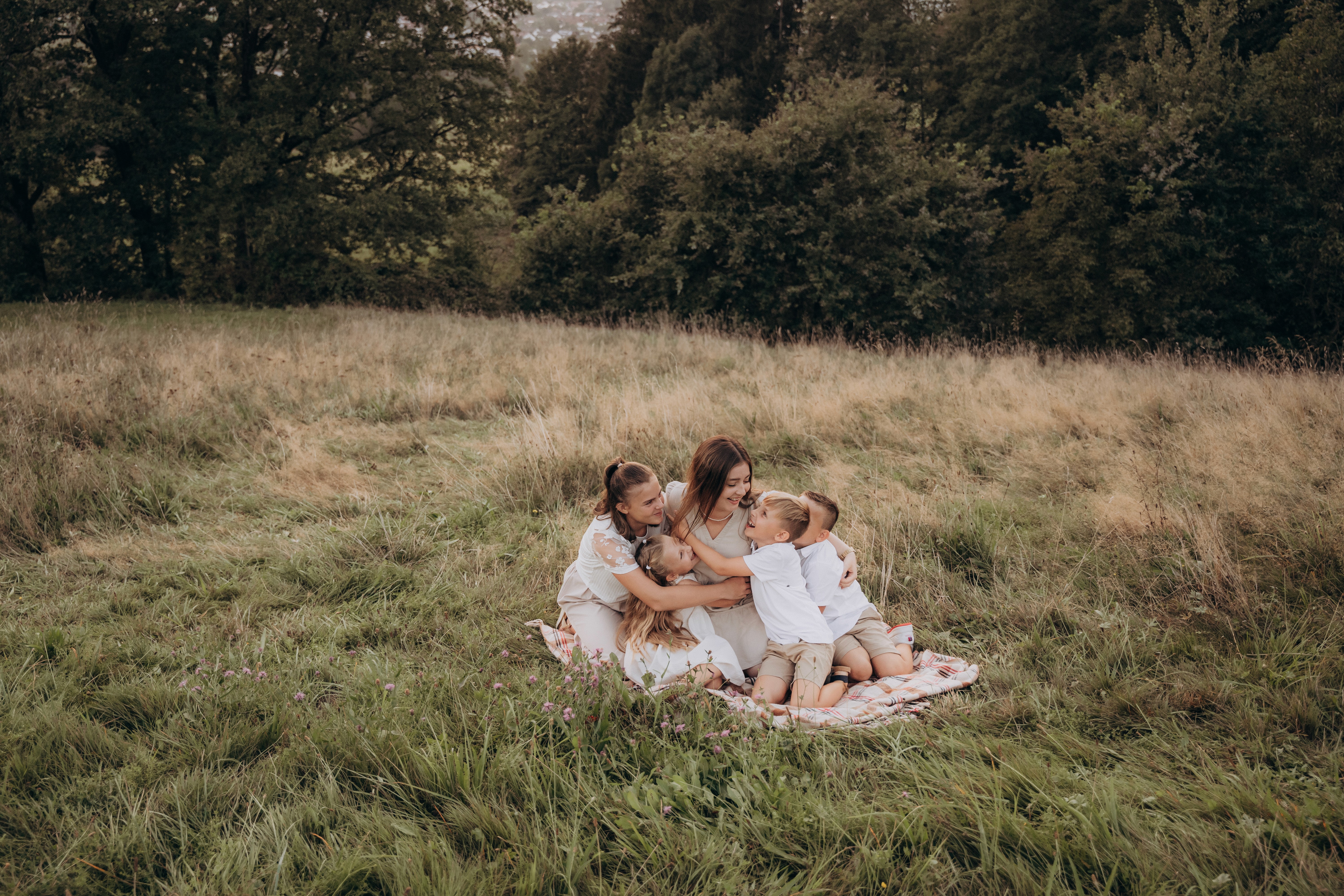 Familienfotografie mit Kindern in Bogen, Bayern – Eltern sitzen mit Kindern auf einer Decke im Grünen.