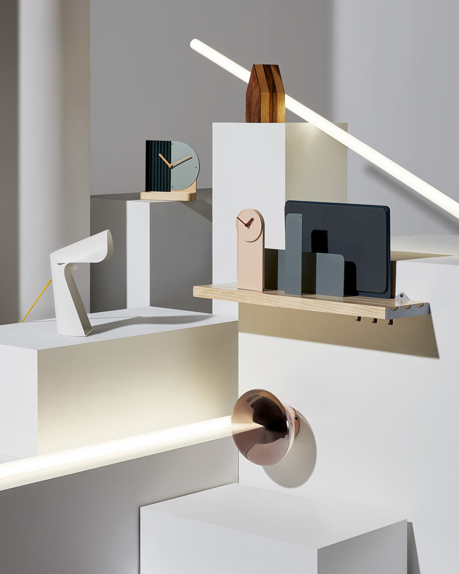 Modern minimalist home decor with geometric clocks and lamps on white platforms.