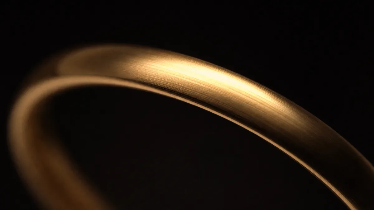 Macro view of a plain smart dhikr ring moving from warm highlight into deep shadow