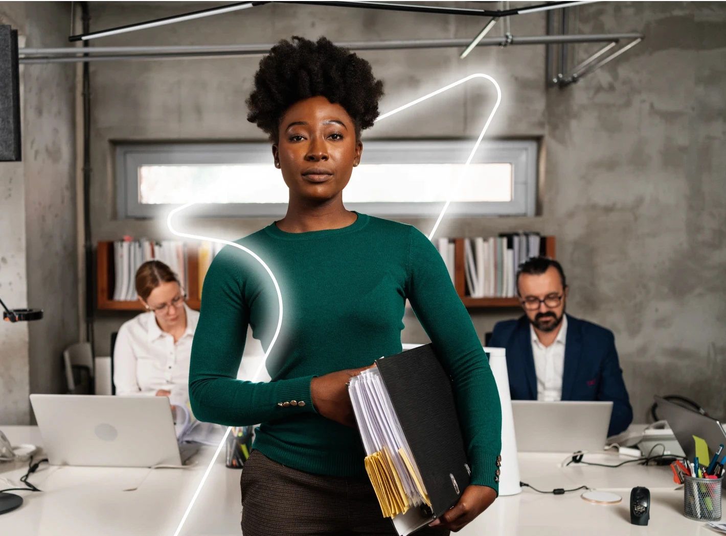 Bureau d'experts-comptables, au premier plan une femme debout et en arrière-plan une femme et un homme en train de travailler