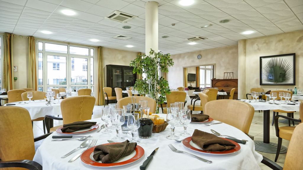 Elegant dining room with warm yellow-gold walls, formally set dining table, decorative furnishings, and bright natural lighting