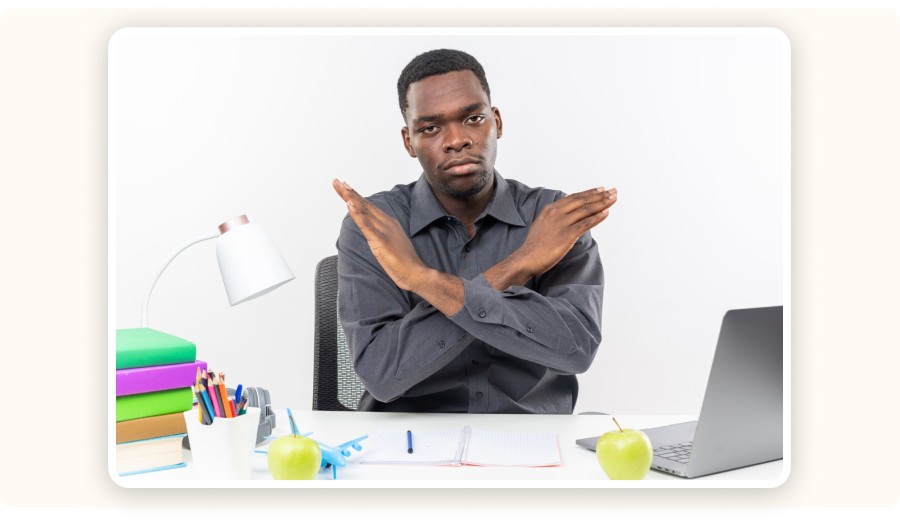 Man at desk crossing arms in refusal gesture