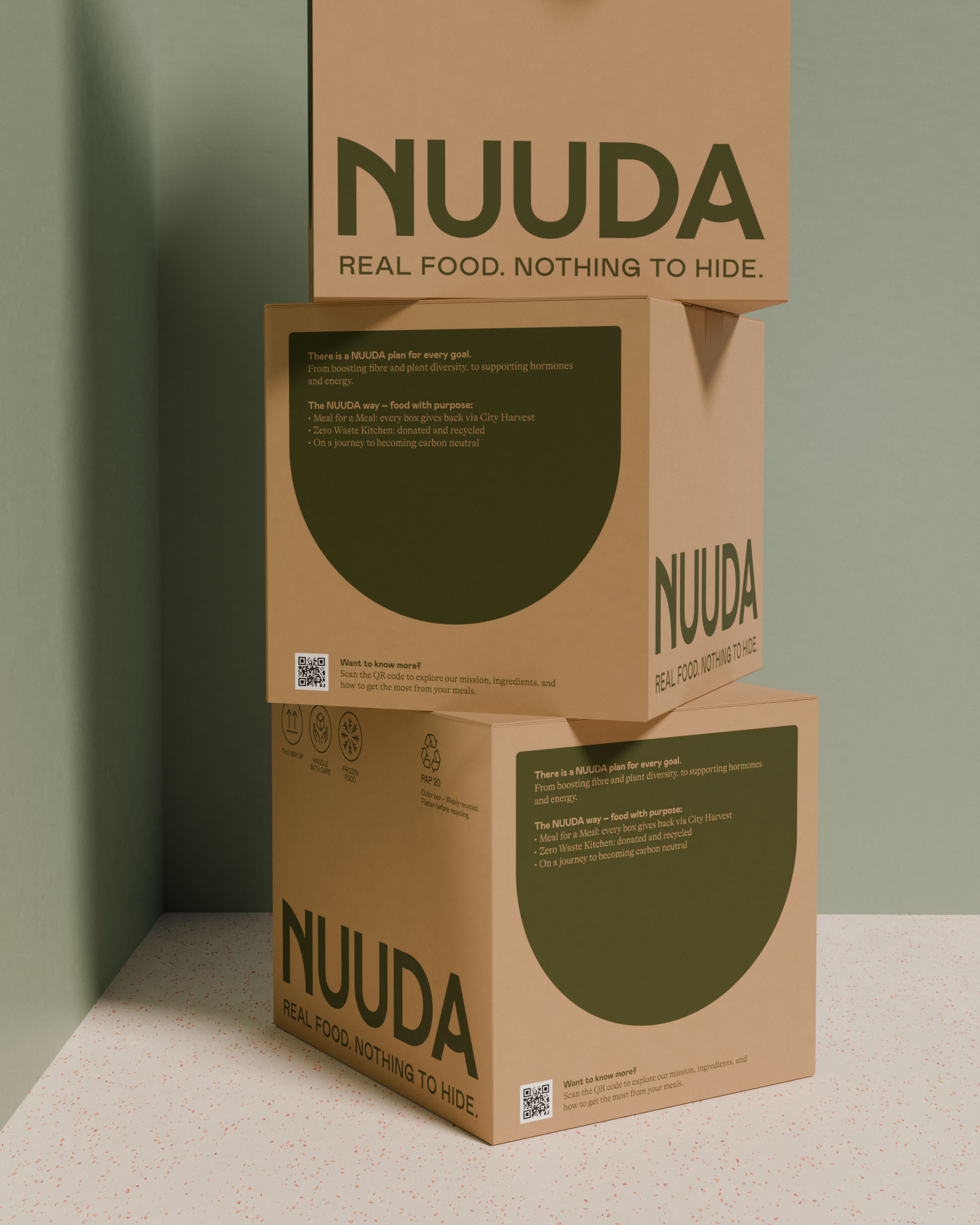 Three stacked Nuuda delivery boxes in kraft cardboard with olive green graphics, tagline, brand messaging, and QR codes