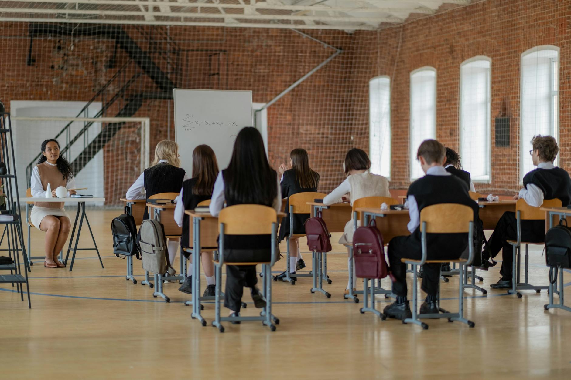 A teacher smiling while pointing to a bright classroom whiteboard during a lesson on student growth.