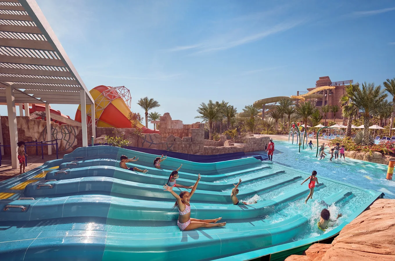 A group of kids cheerfully going down Aquaventure’s water slides.