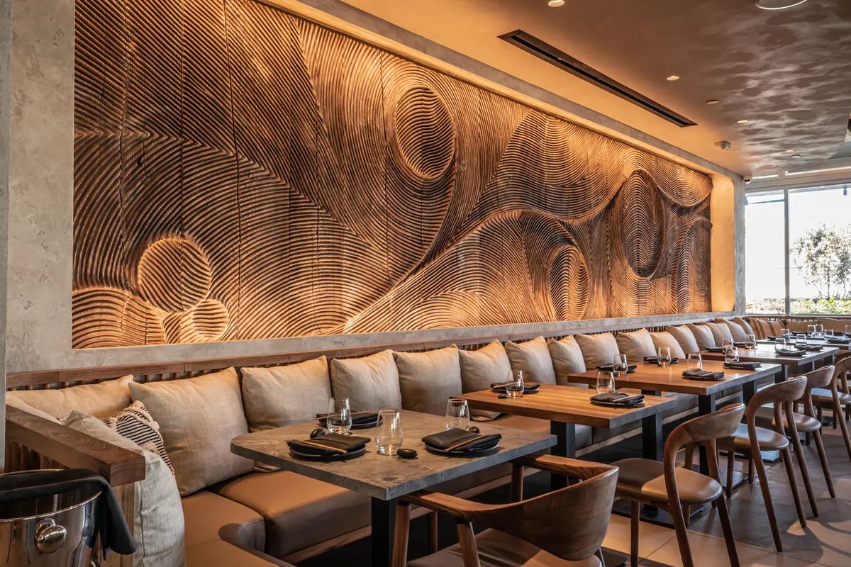 Golden hour lighting illuminating Dhoom’s textured feature wall and cozy seating, highlighting the restaurant’s shift into a warm, intimate evening dining atmosphere.