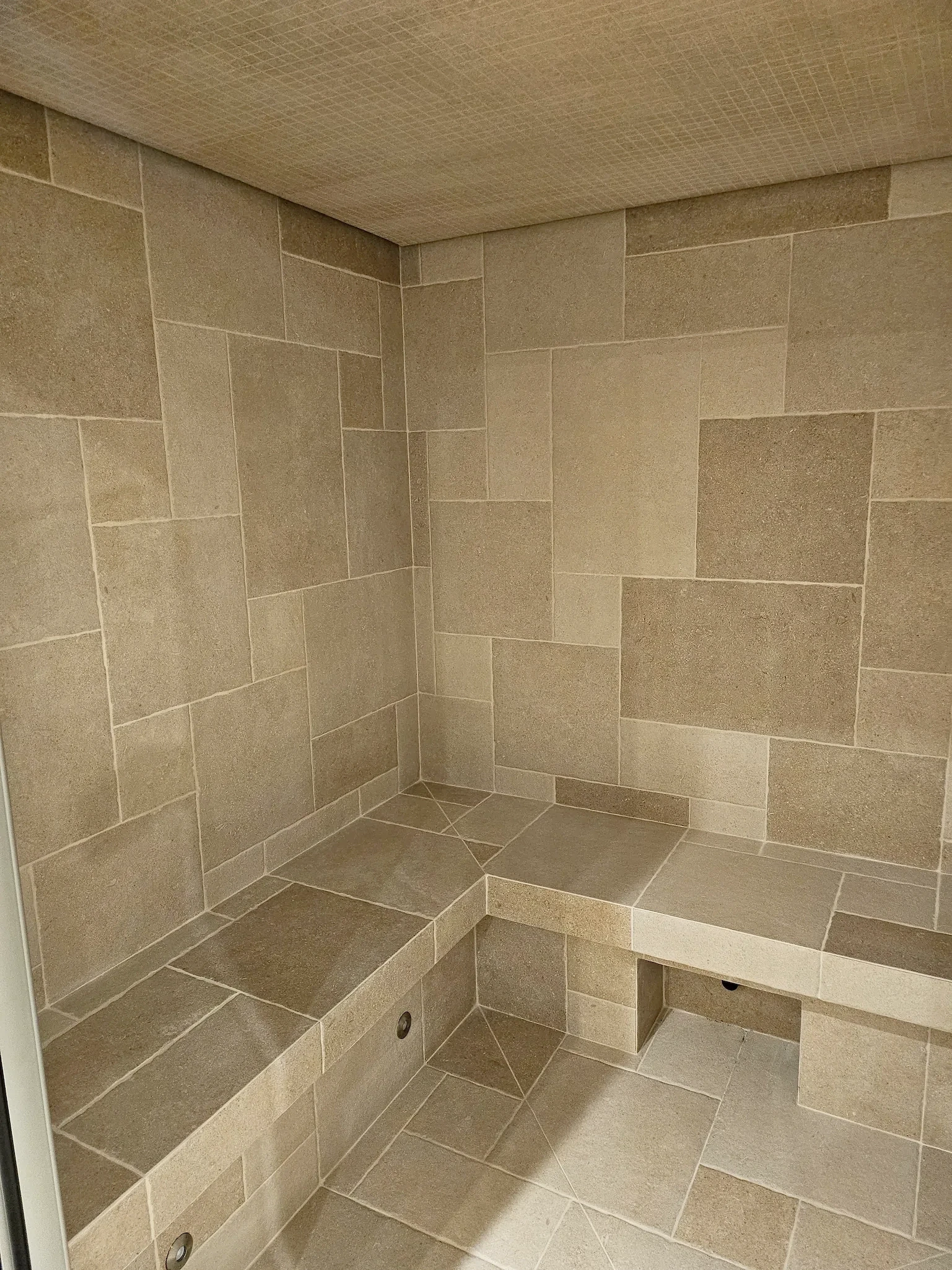 Sauna en bois clair avec pierres chaudes et bancs pour la détente.