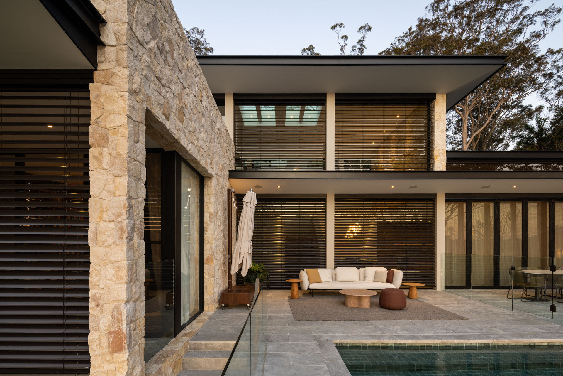 Close-up of a modern building facade featuring vertical wooden panels and black-framed windows, with natural light casting tree shadows on the surfaces.
