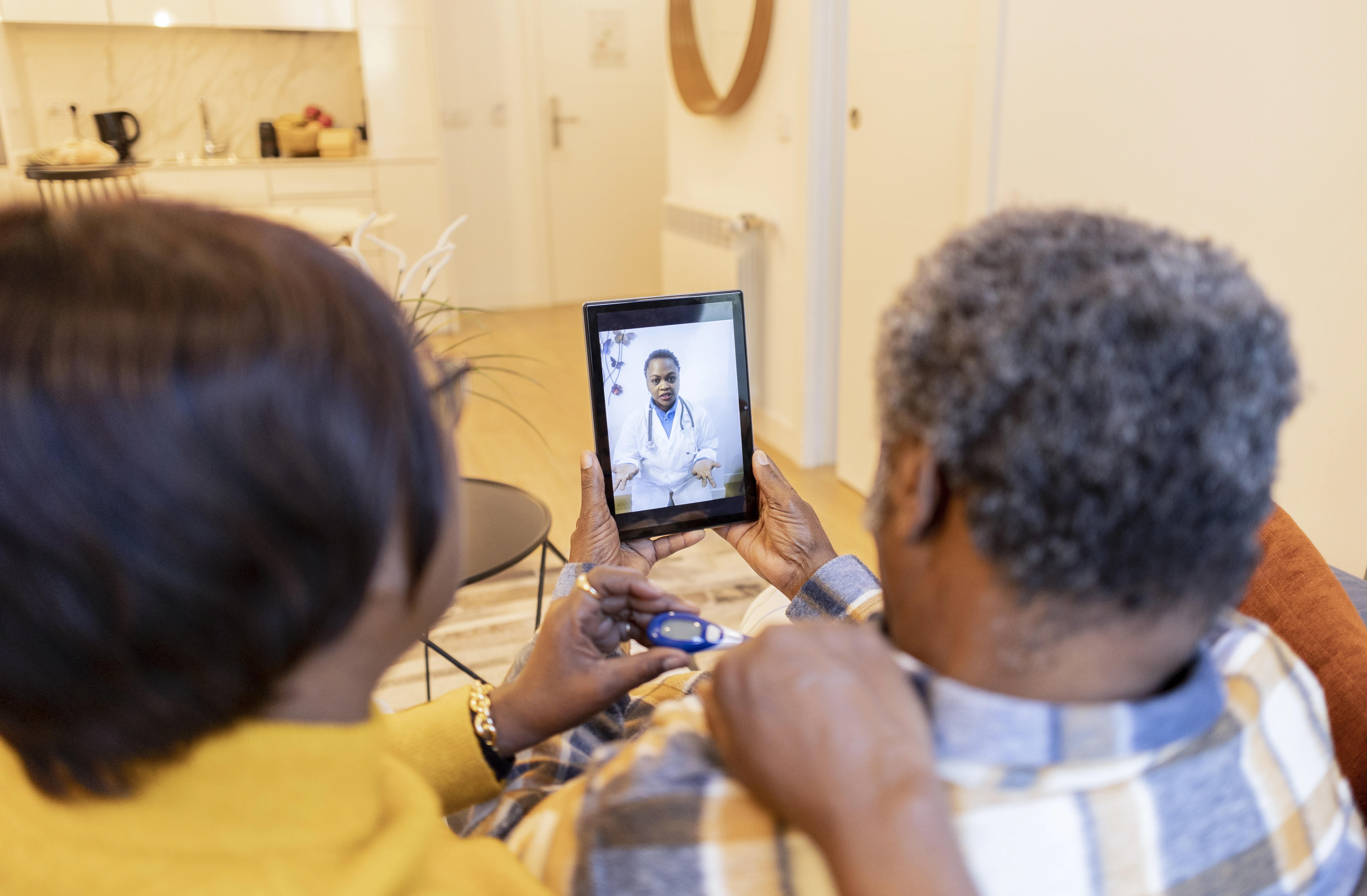 African American Senior Couple talk their doctor video call from home