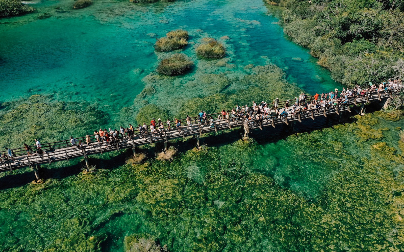 克罗地亚克尔卡国家公园，游客们在一座木桥上观赏碧绿的河水。