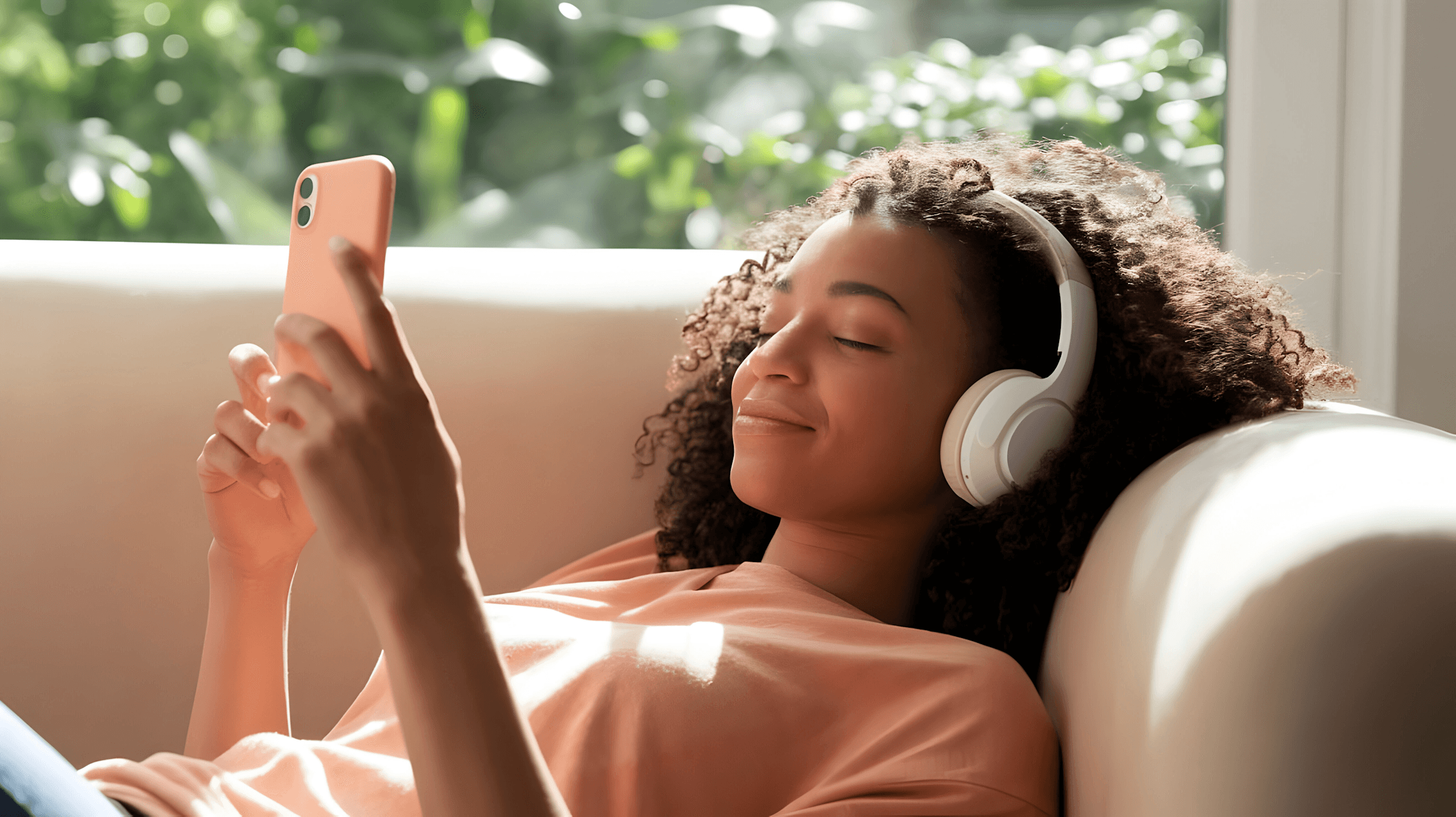 Woman using phone with headphones on sofa
