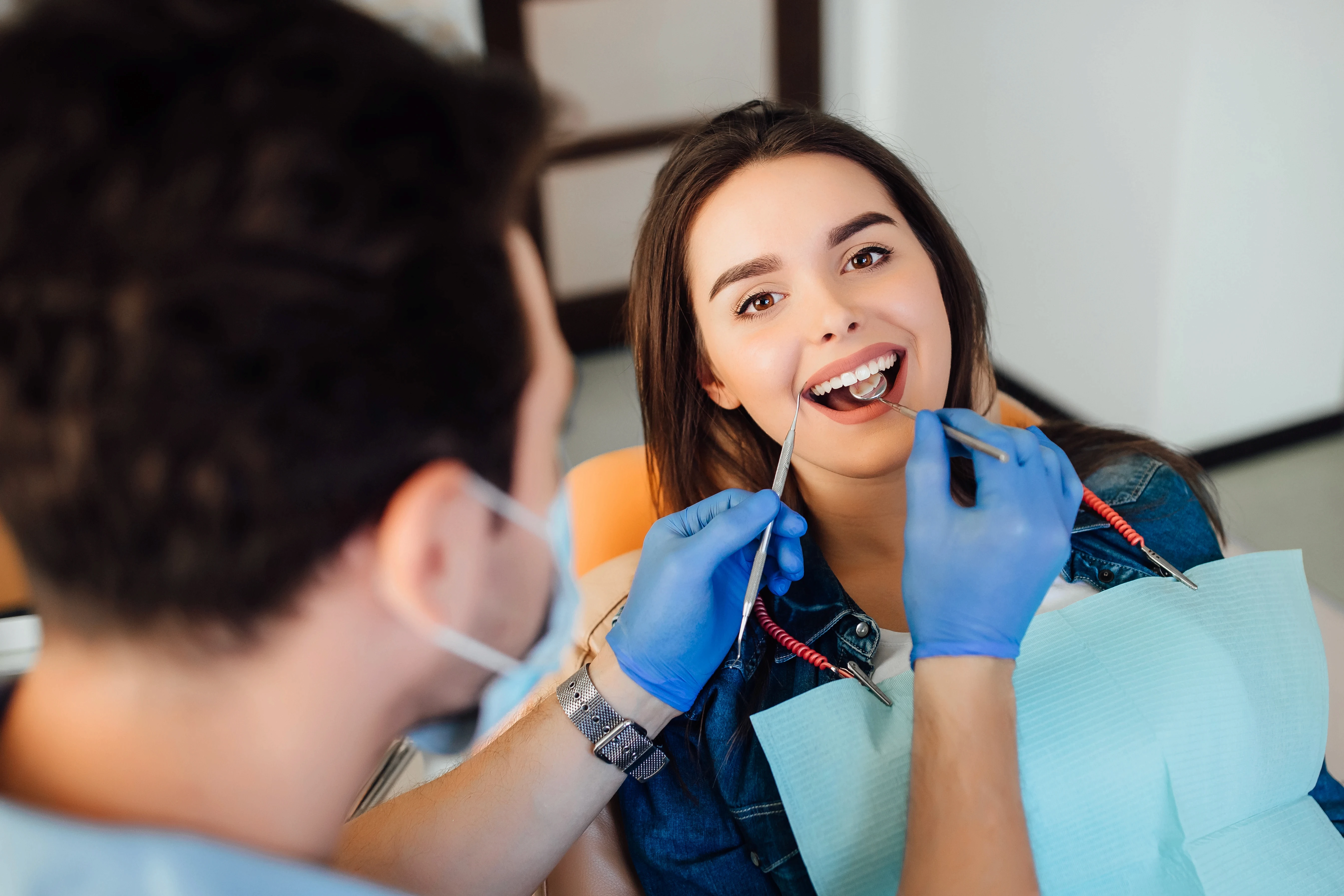 Smiling patient during dental checkup with dentist examining teeth