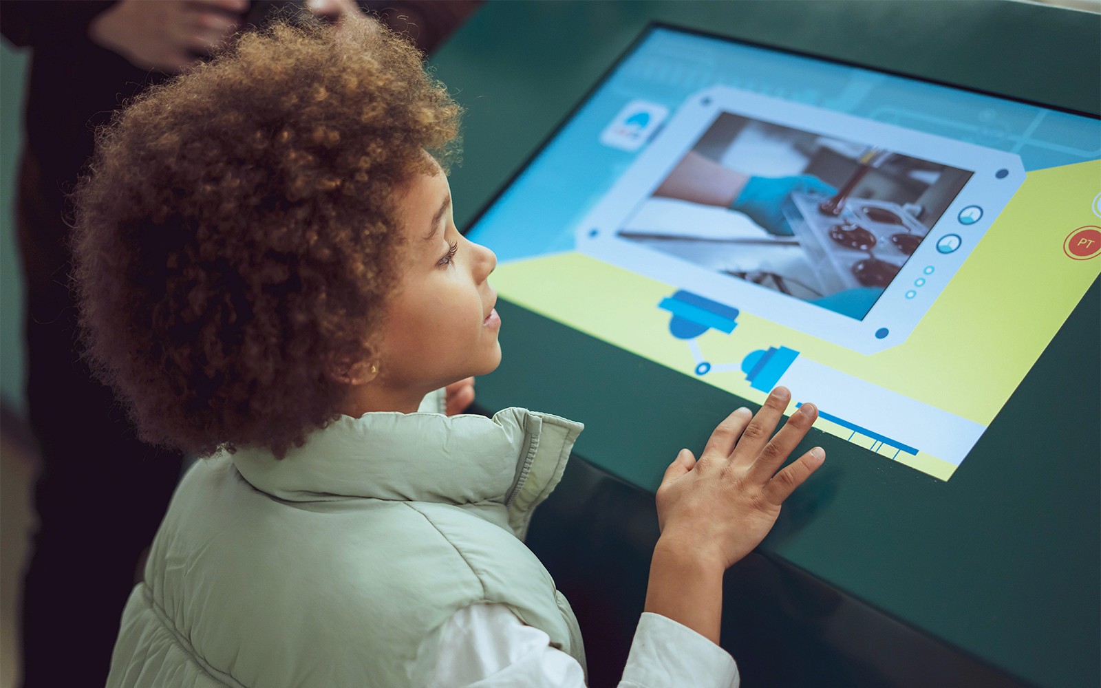 Gyerek érintőképernyővel játszik a Csokoládé Története Múzeum kiállításon.