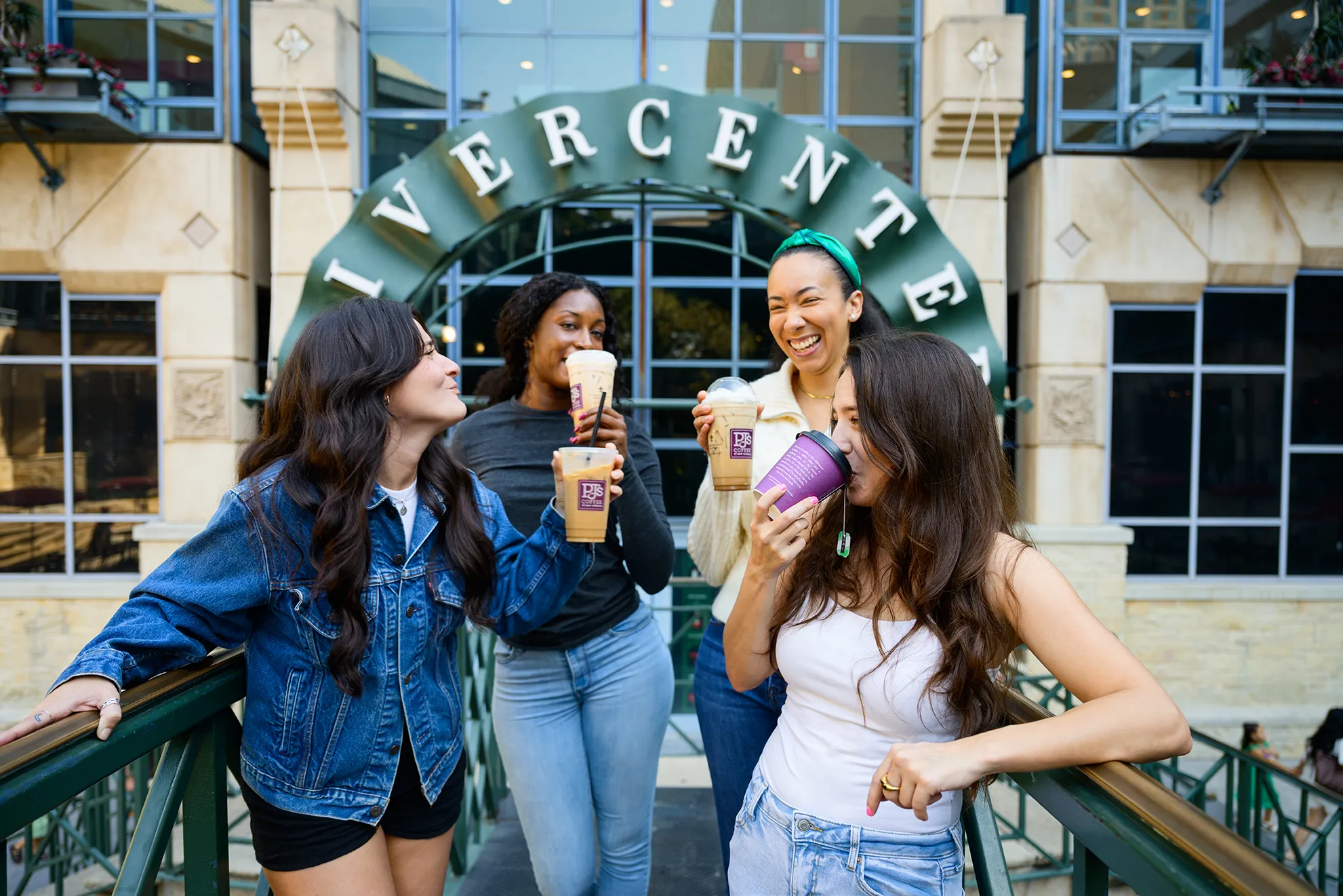 Four friends enjoying coffee drinks together outside the Rivercenter entrance