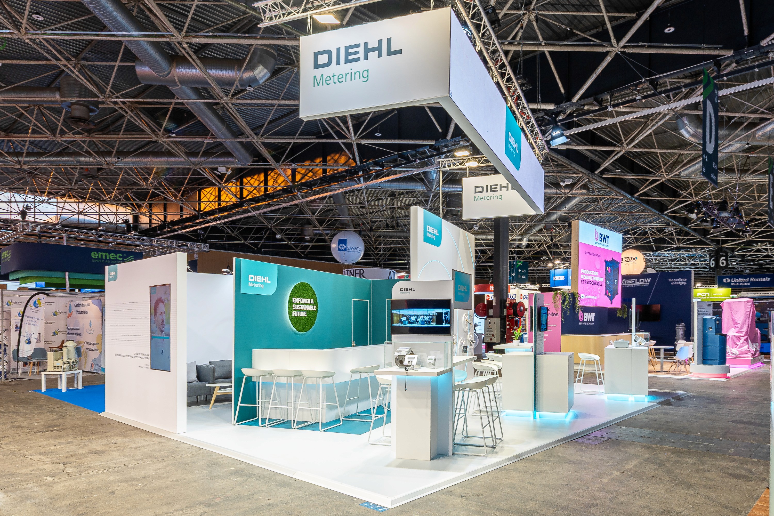 Stand Diehl Metering Pollutec 2025 réalisé par Expace – vue frontale du stand avec zone analyse des données, présentation compteur Altair V5 et mur produits à rétroéclairage blanc