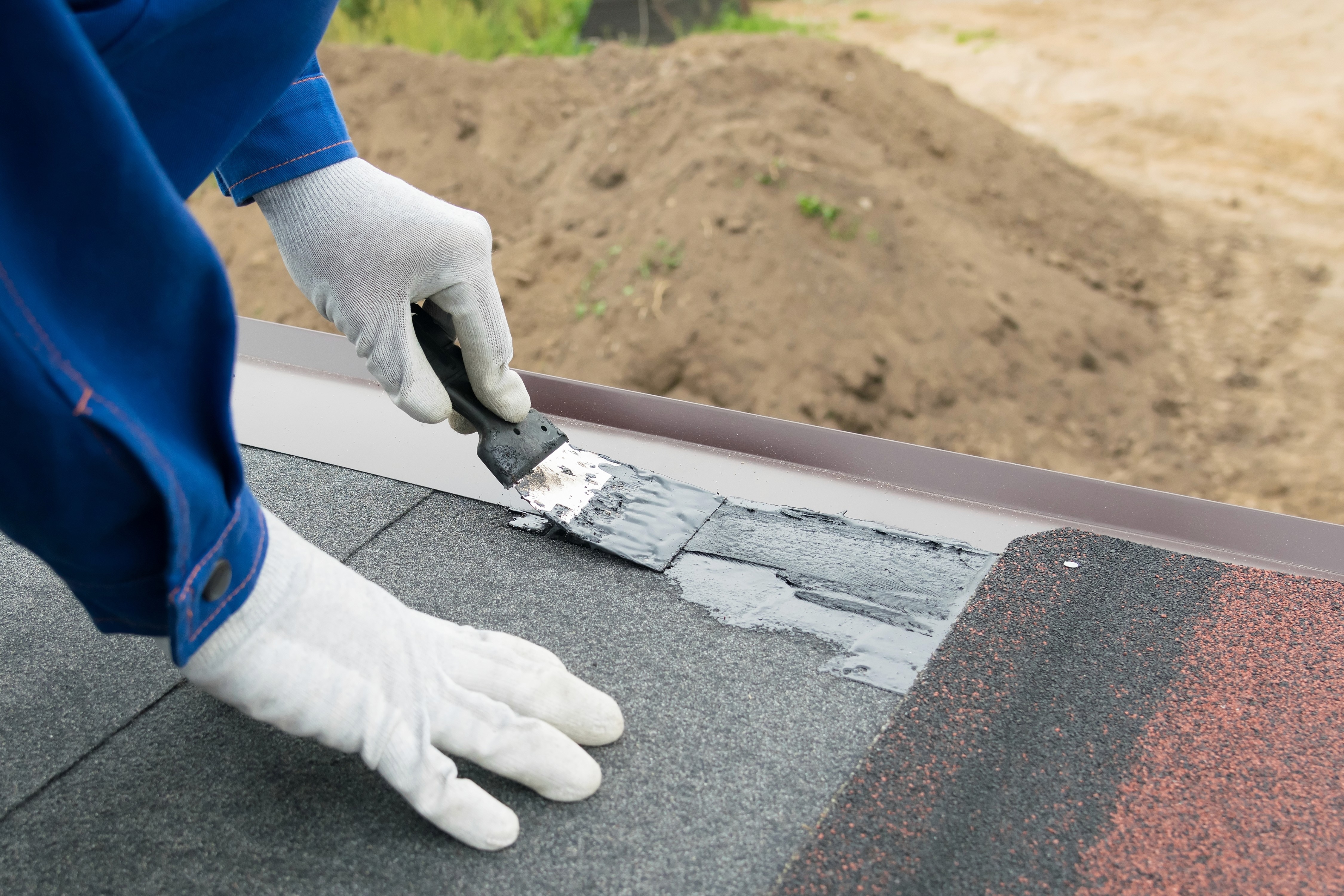 a worker covers the cracks with sealant on the roof