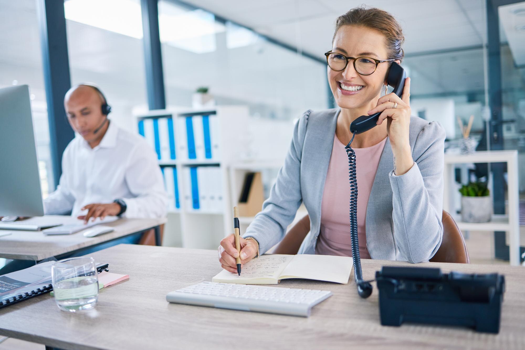 Glimlachende receptionist aan bureau met telefoon in een professioneel kantoor