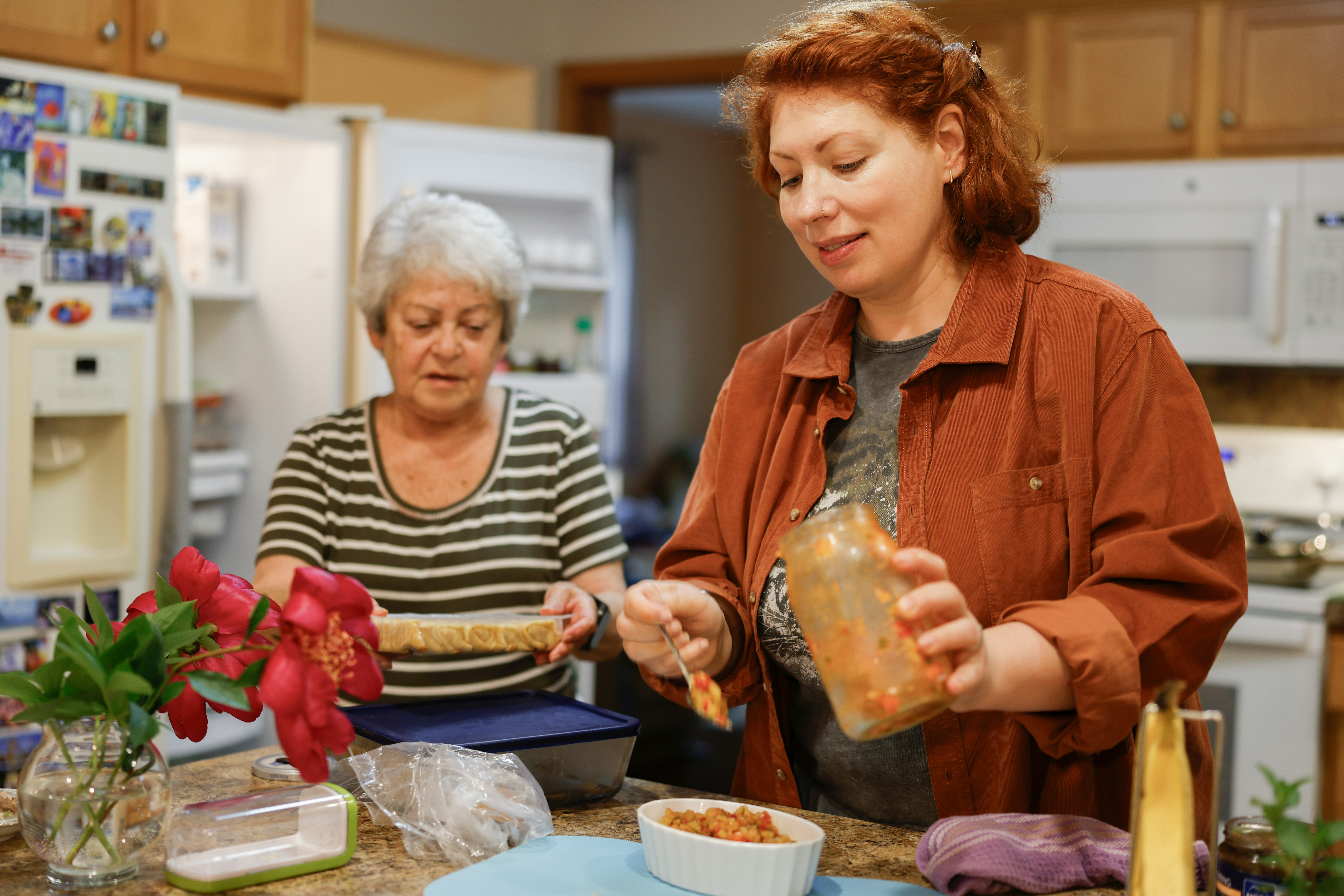 Two women preparing food in a kitchen.