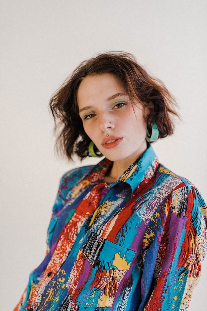 Portrait of woman in a colorful shirt in a natural light studio