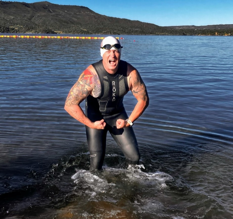 An open-water swimmer wearing a cap and goggles moves through the water.