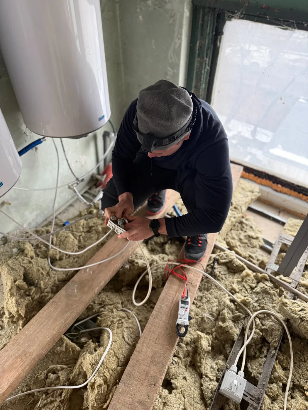 Ampermax villanyszerelő padlástérben végez elektromos vezetékezést szigetelés között