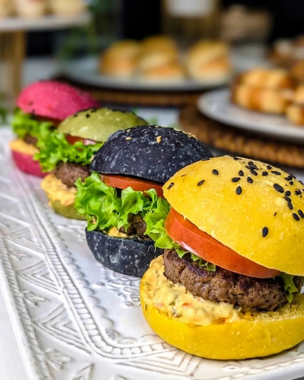 Mini hamburguesas gourmet de colores para banquetería premium a domicilio.