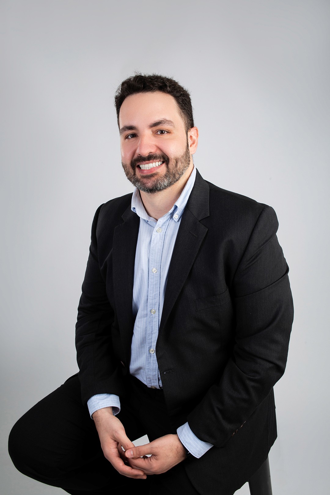 Image of doctor Vinícius Salgado sitting at his office desk looking and smiling at the camera.