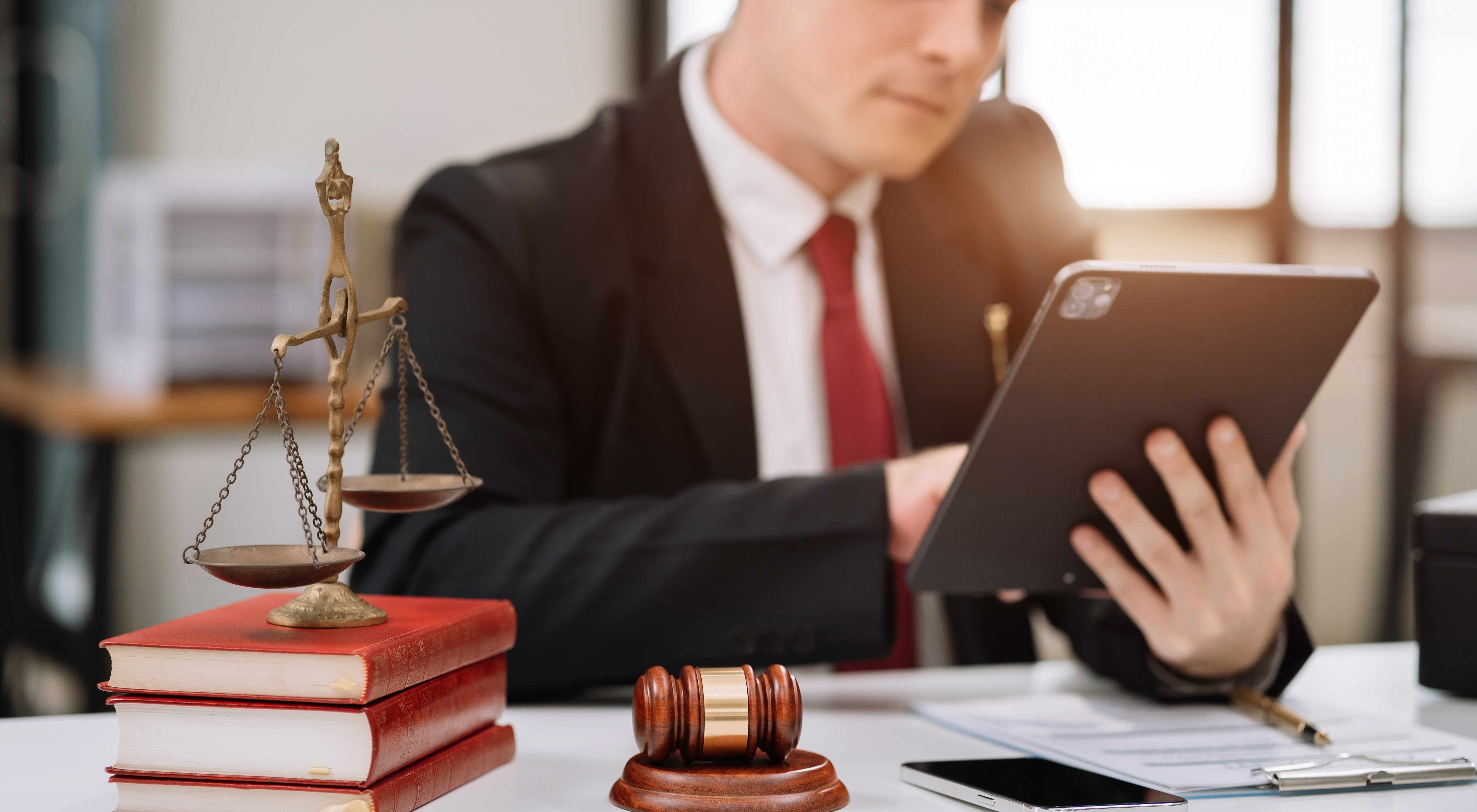 Image of a lawyer at a desk reviewing documents beside a laptop or tablet.
