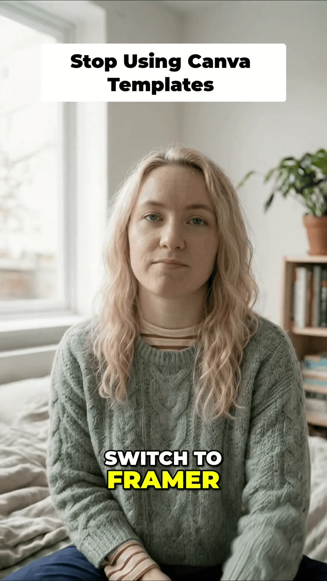 Blonde woman in a sage green cable-knit sweater sitting on a bed, smiling warmly, with a bookshelf and potted plant visible in the background