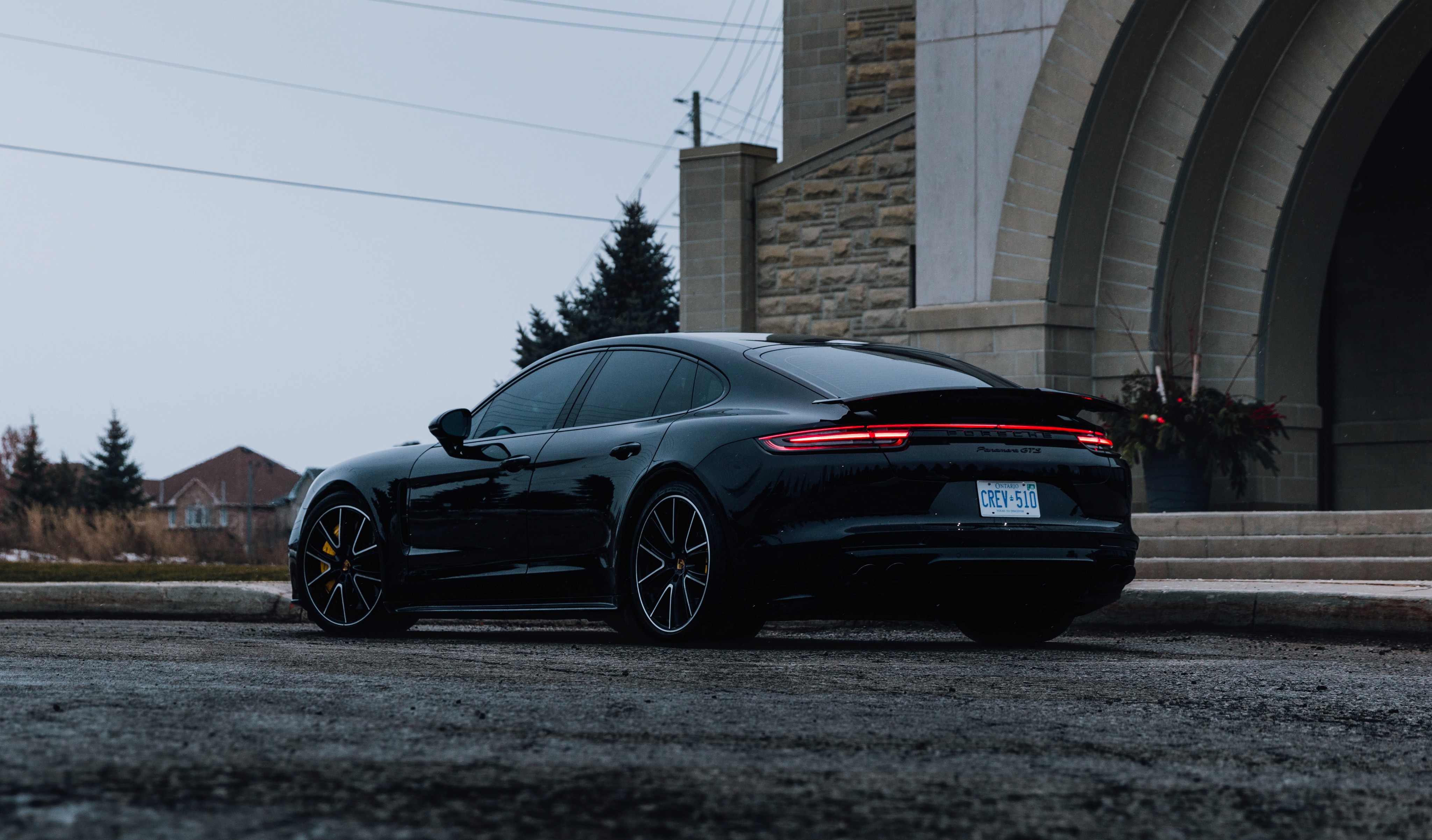 a black porsche outside, photo from sideways behind