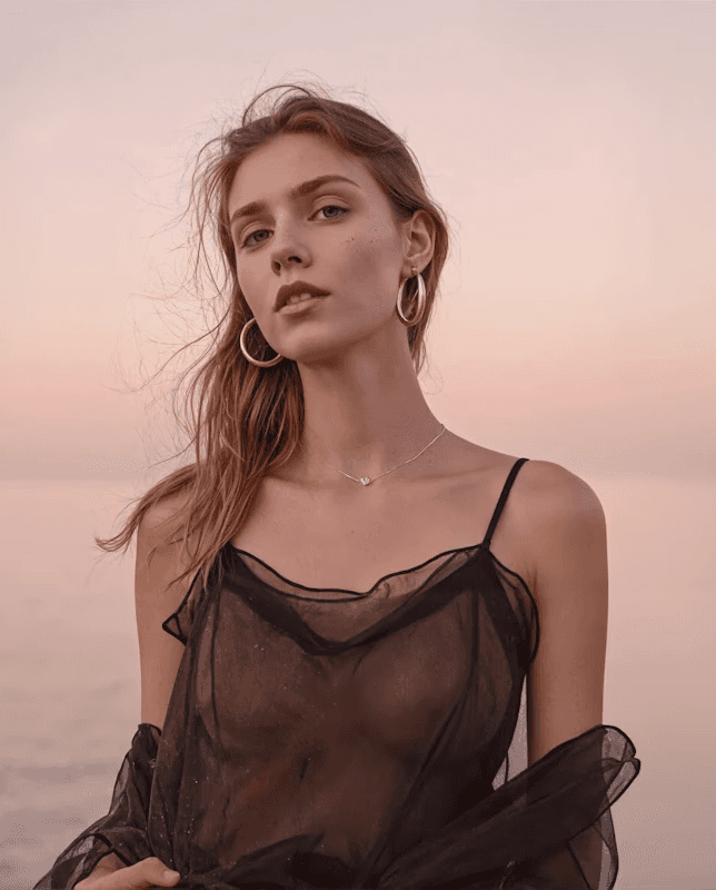 Woman meditating in forest sunlight beside a calm blue lake.