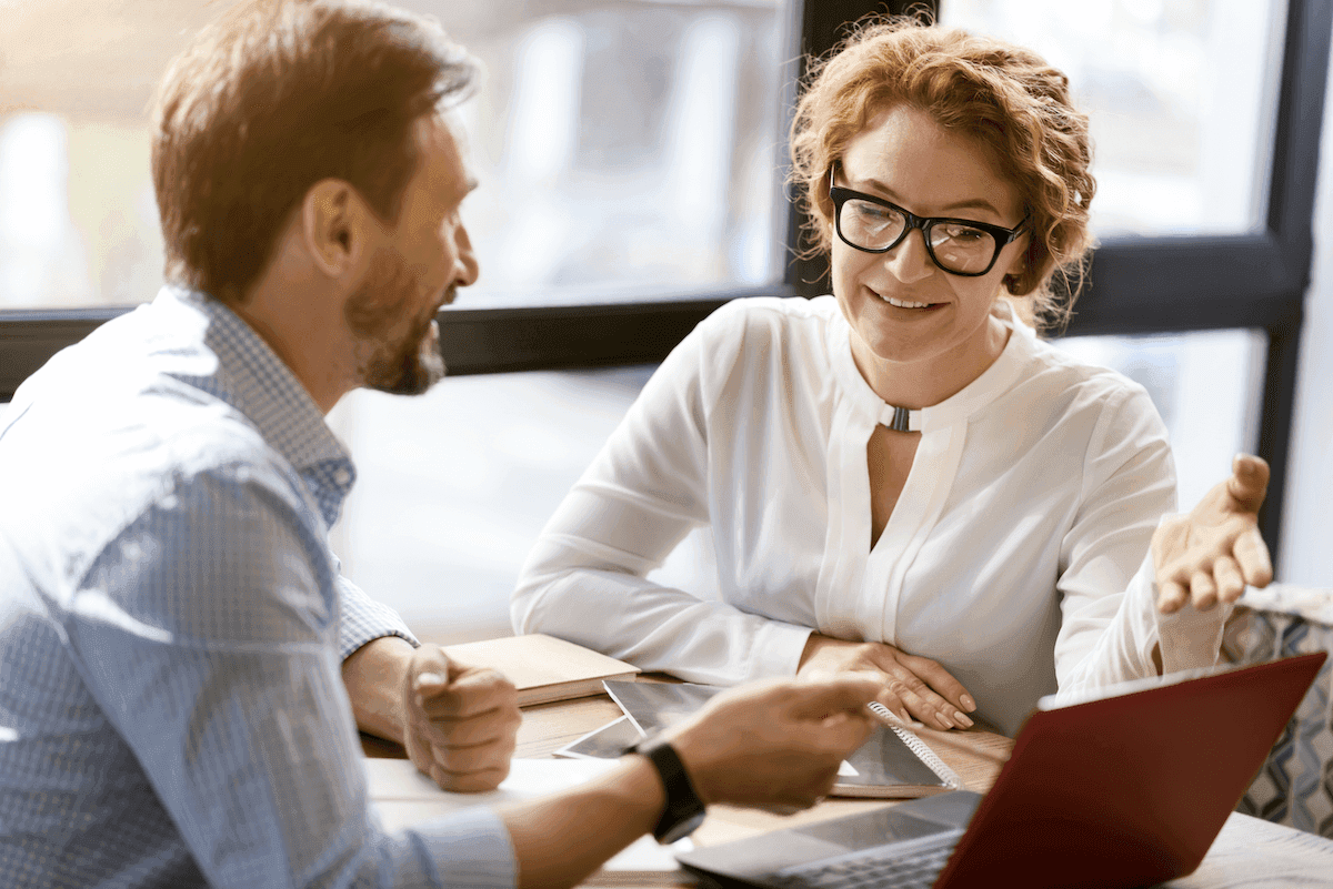 SPIN selling: Two people having a discussion while looking at a laptop