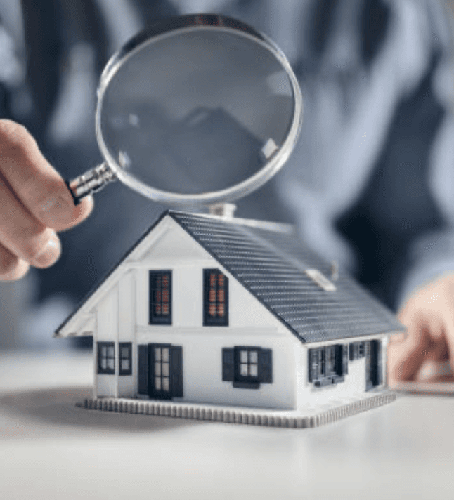 person standing with magnifying glass looking at a home