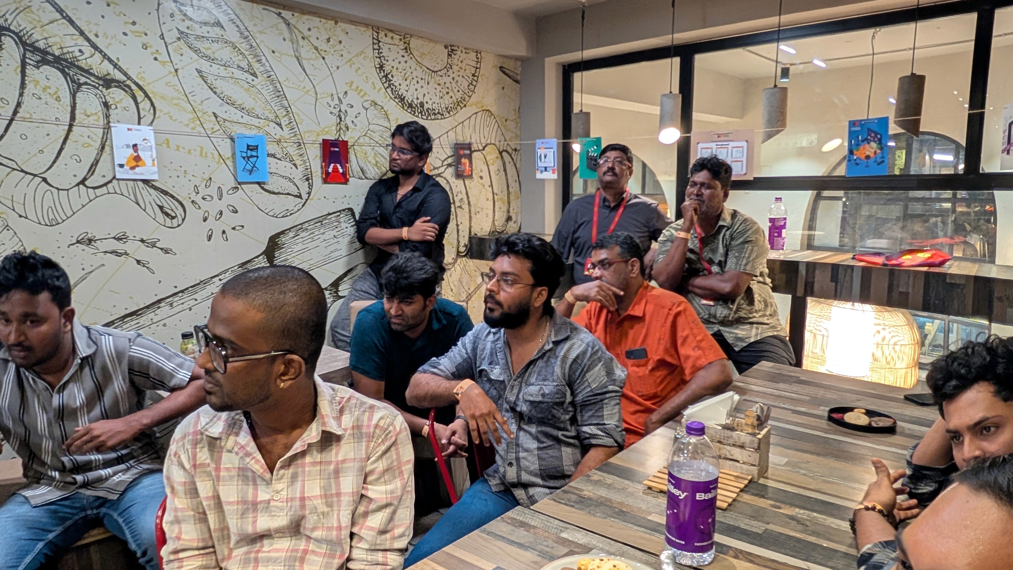 person discussing while standing in front of a large screen in front of people inside dim-lighted room