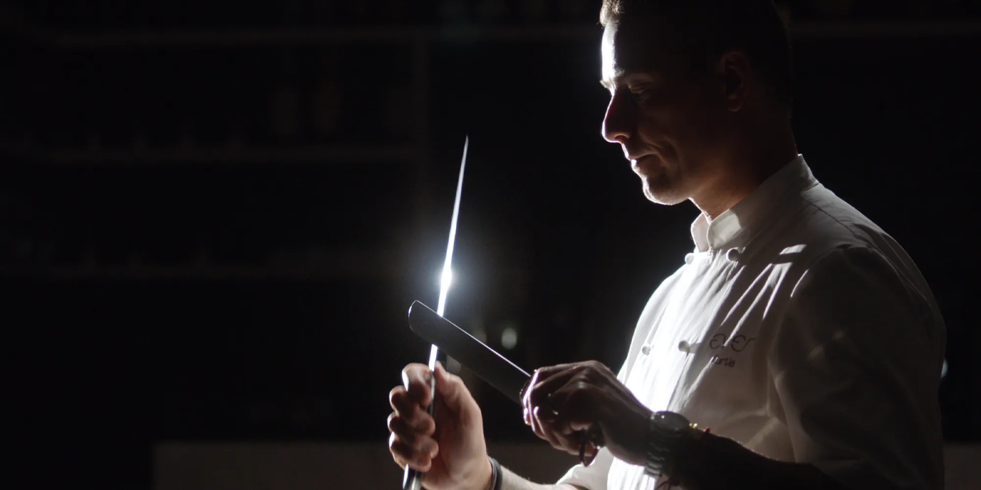 Official Ever After film publicity still showing Curtis Duffy in his chef’s coat sharpening a knife.