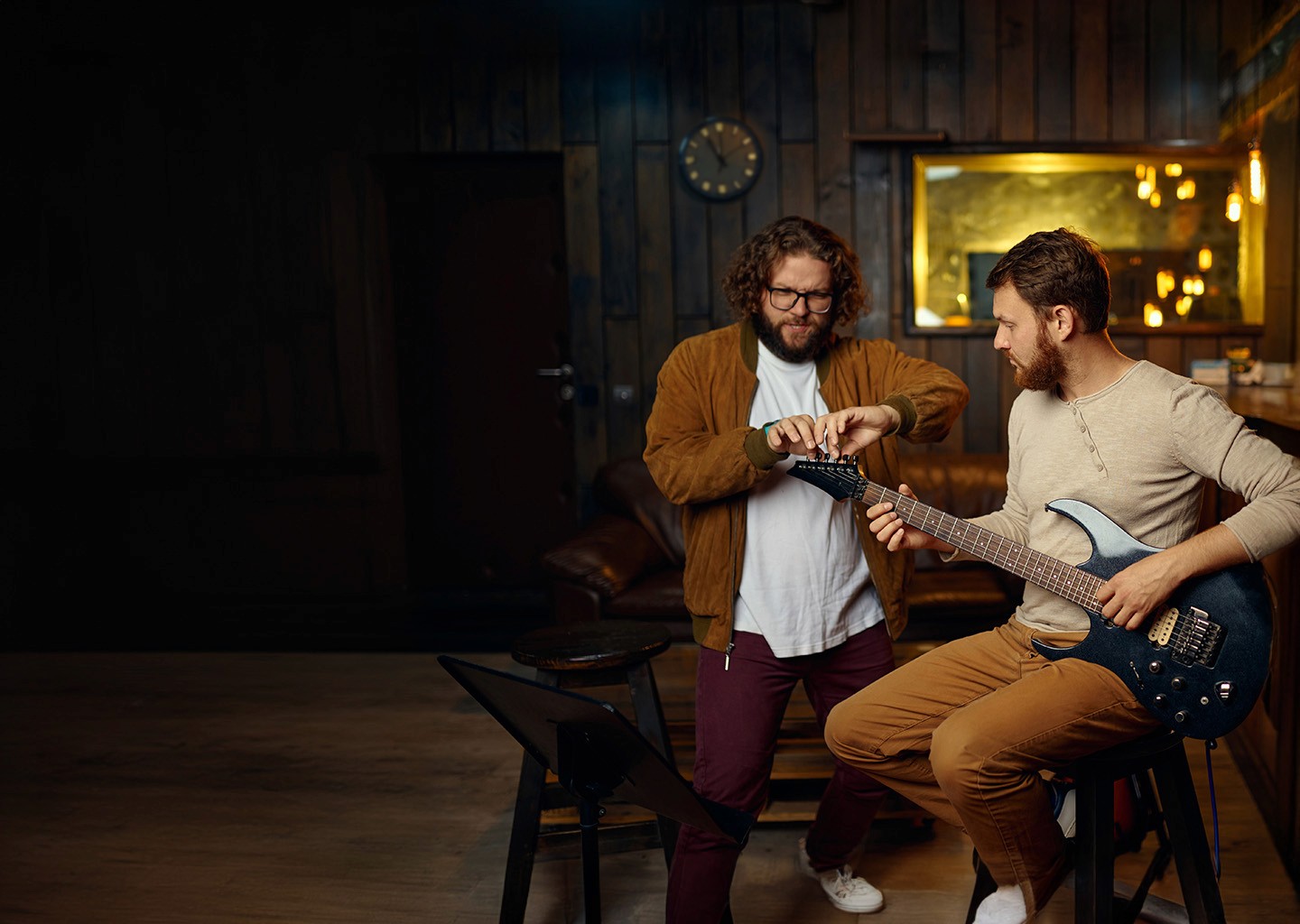 Guitar teacher helping student tune his guitar