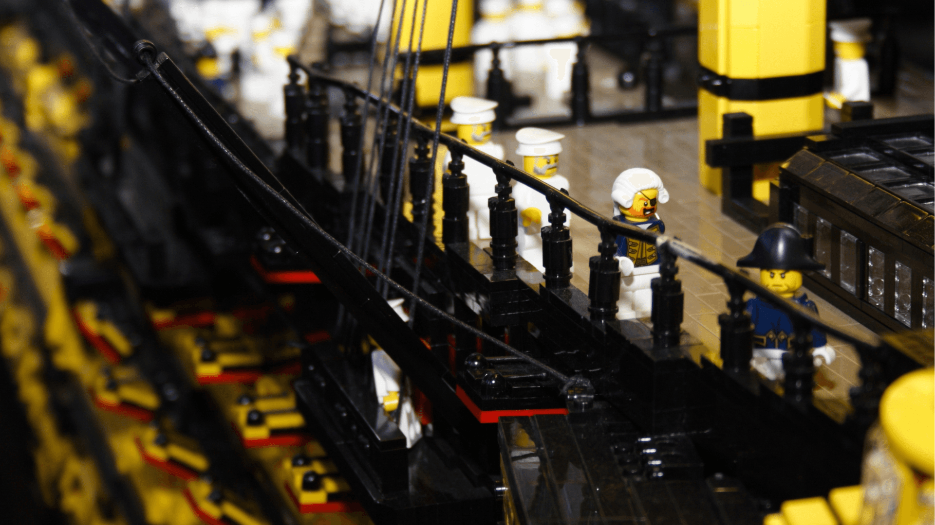 Four LEGO® sailors stand on top of the mast of the LEGO® HMS Victory ship.