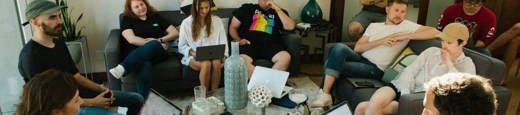Group of people collaborating in a casual meeting room setting.