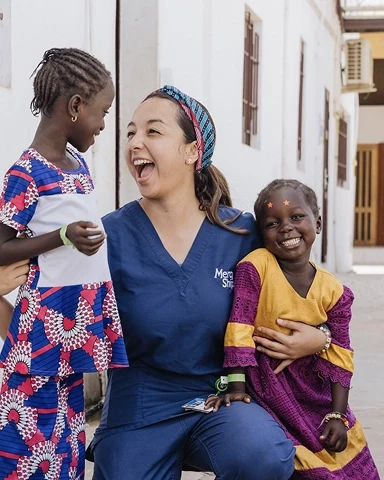 Volunteer smiling with two children