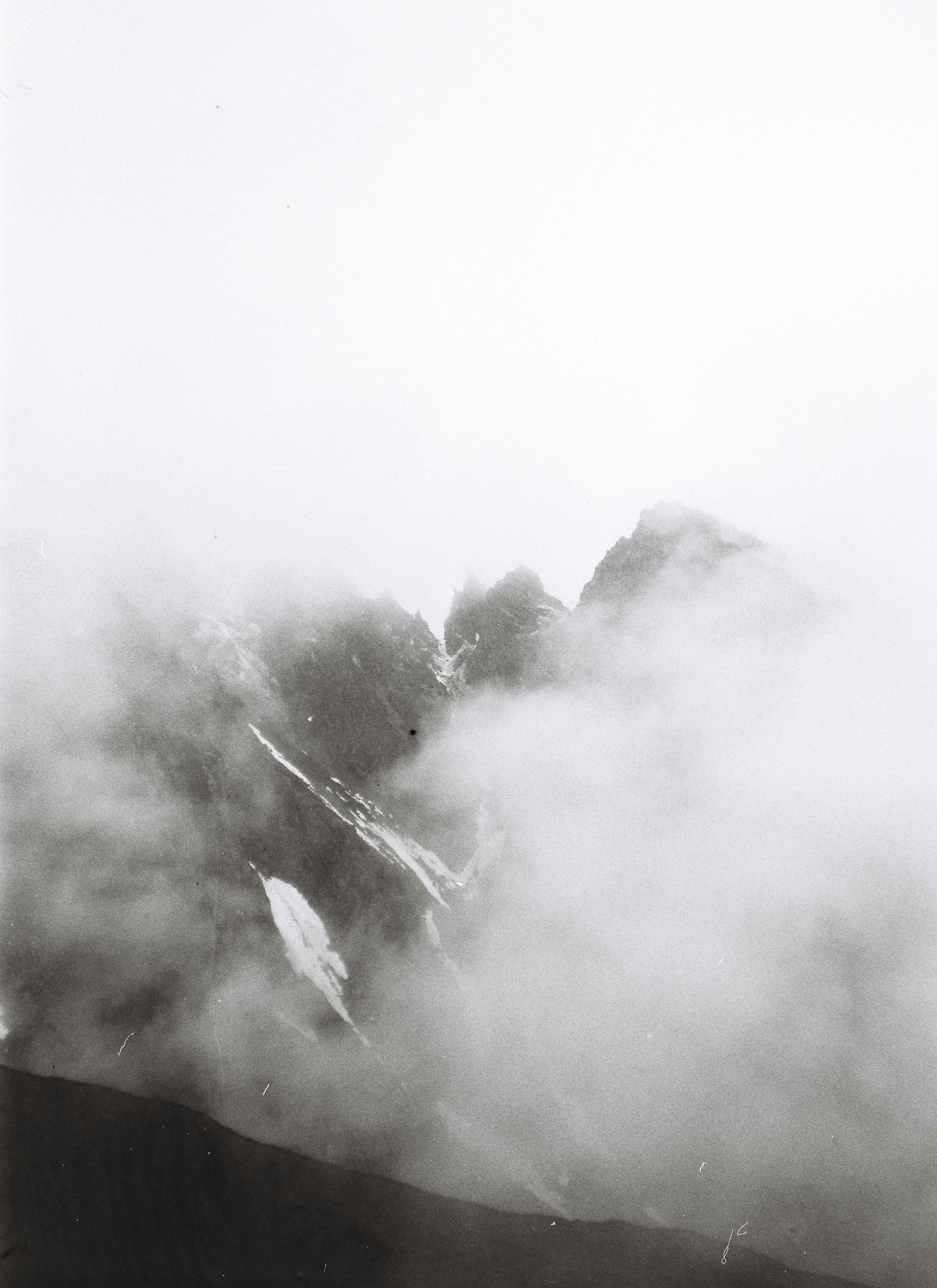 a black and white photo of a mountain covered in fog