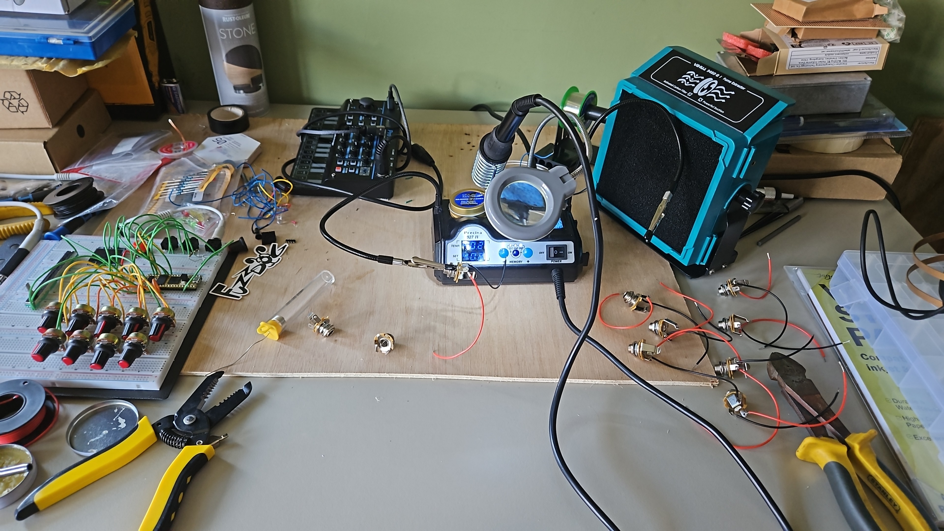 A modified electric guitar on a workbench alongside soldering equipment and electronic parts