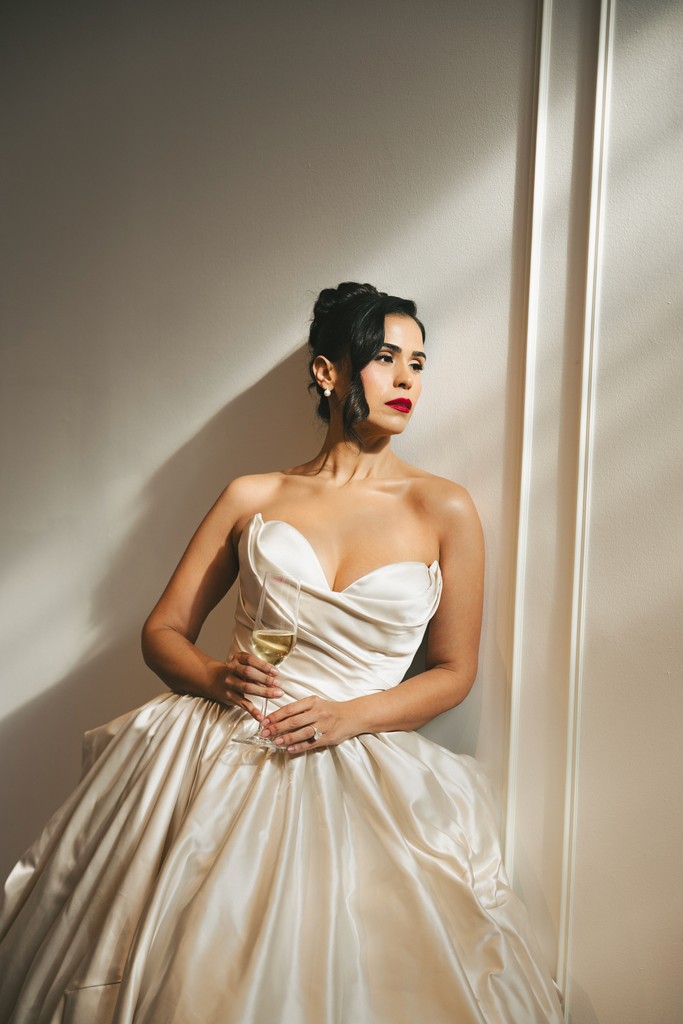 Wedding photographer in South Florida captures a bride walking across the room in her robe with her wedding dress hanging on the wall.