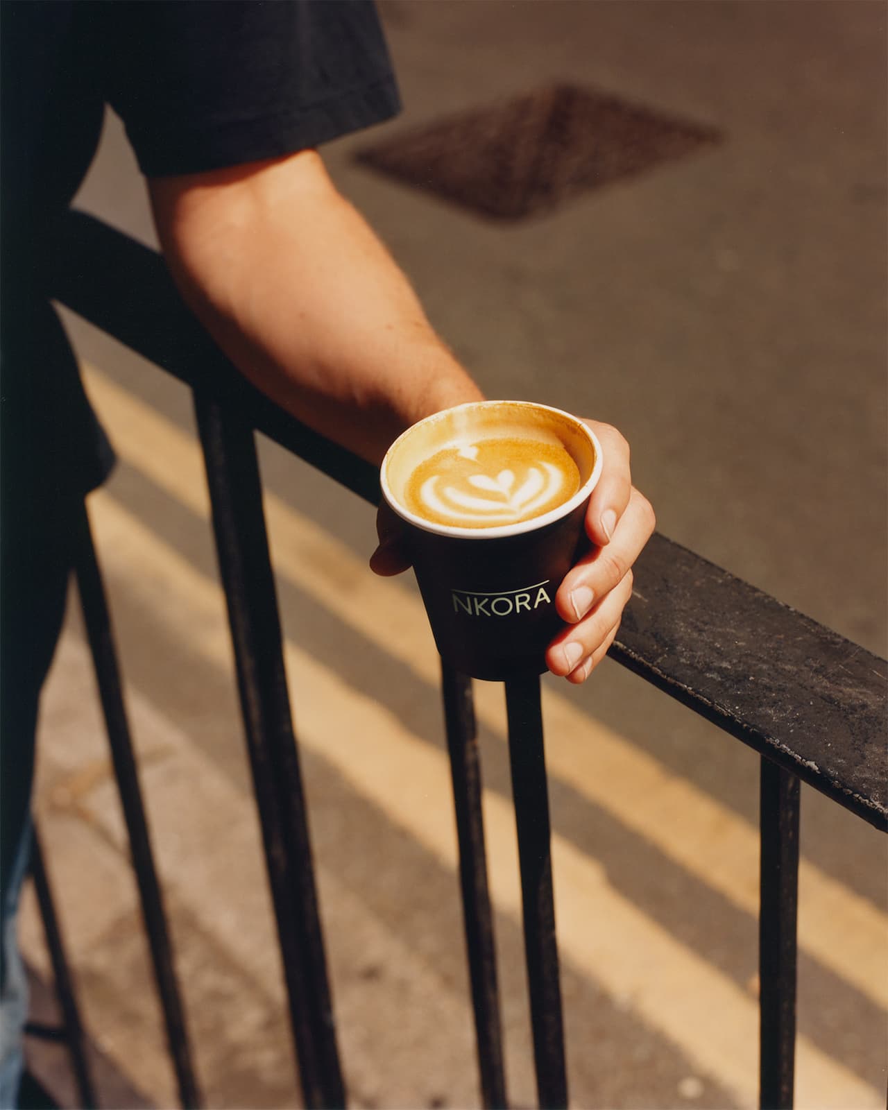 A personal holding a NKORA coffee cup outdoor