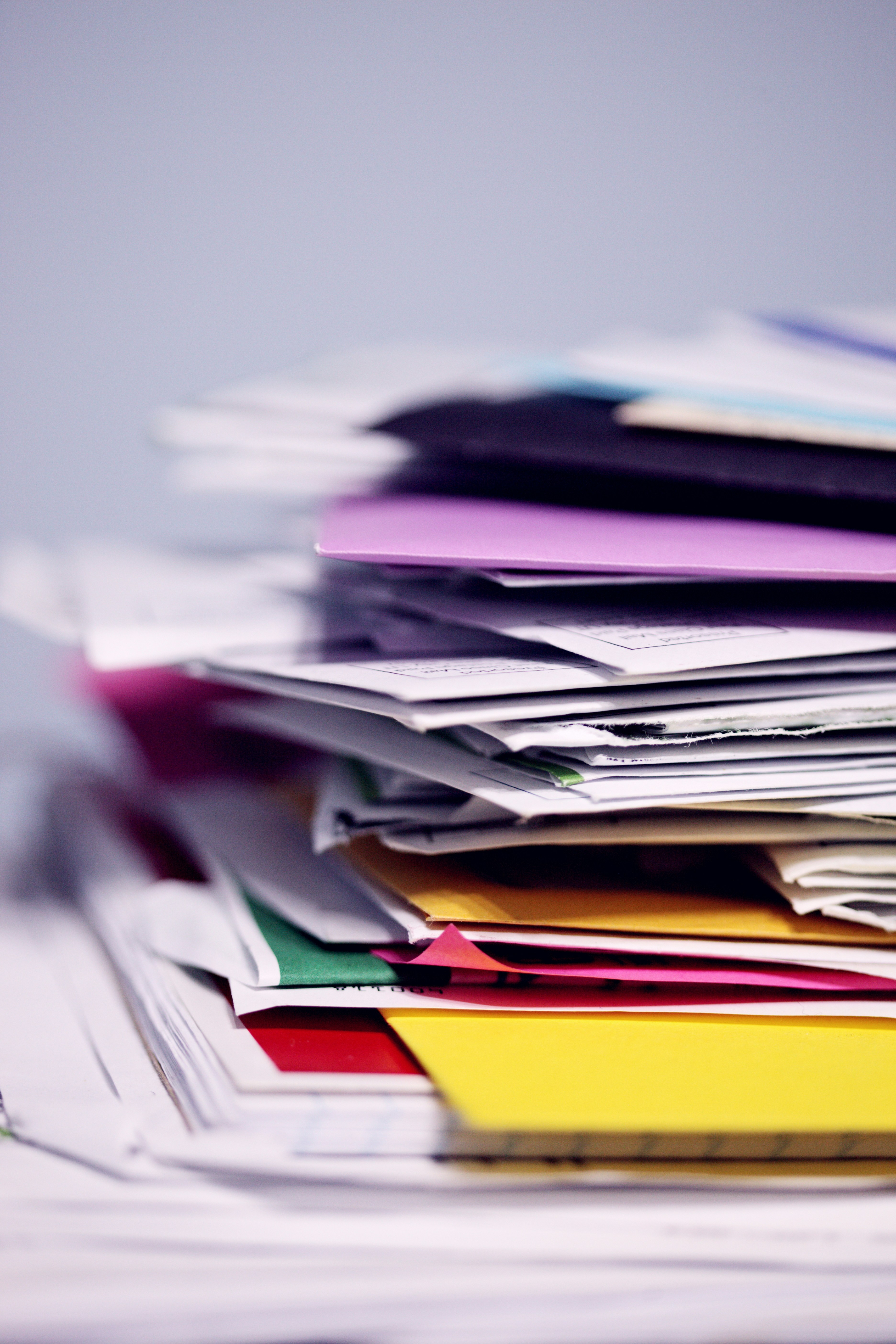 Stacks of assorted paperwork and files piled high on a desk, symbolizing the need for effective document management.