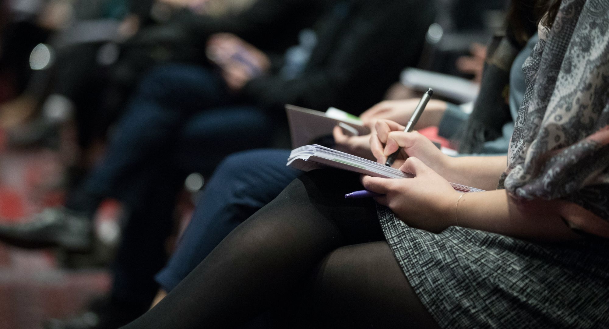 pessoas sentadas fazendo anotações em cadernetas