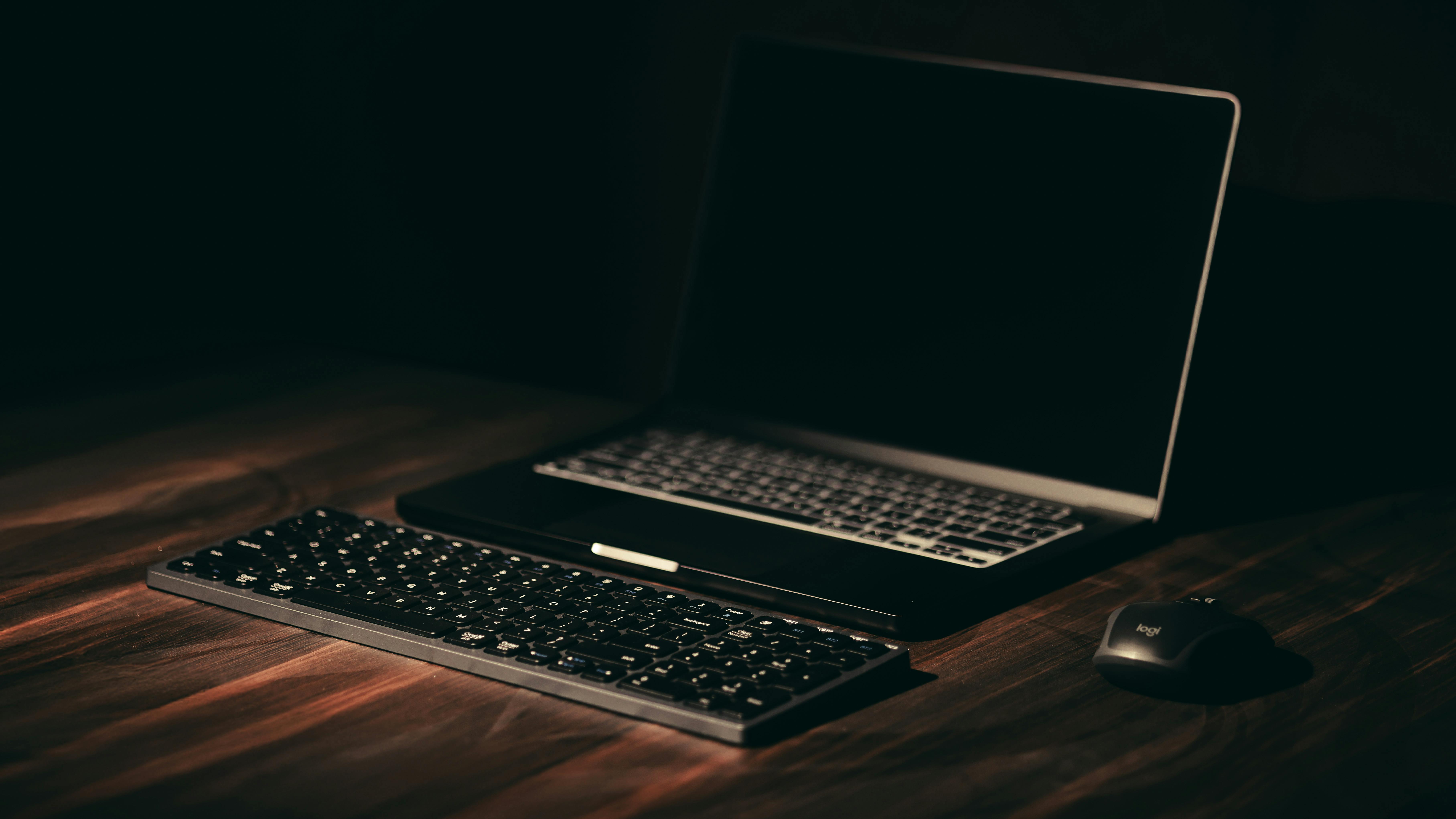 man sitting facing silver MacBook inside room