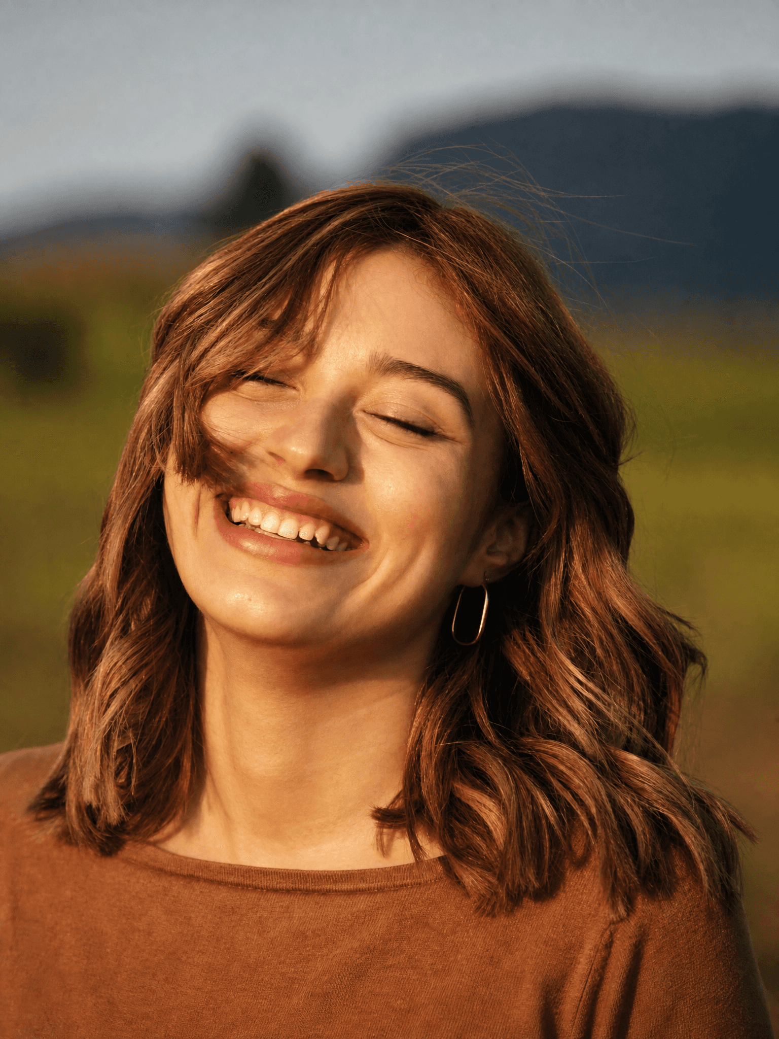 Close-up of a smiling woman outdoors with sunlight in her hair